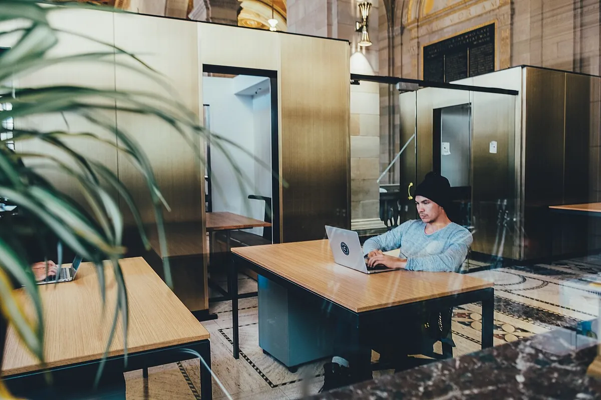 Bureau vitré d’un espace de travail, une personne installée à sa table