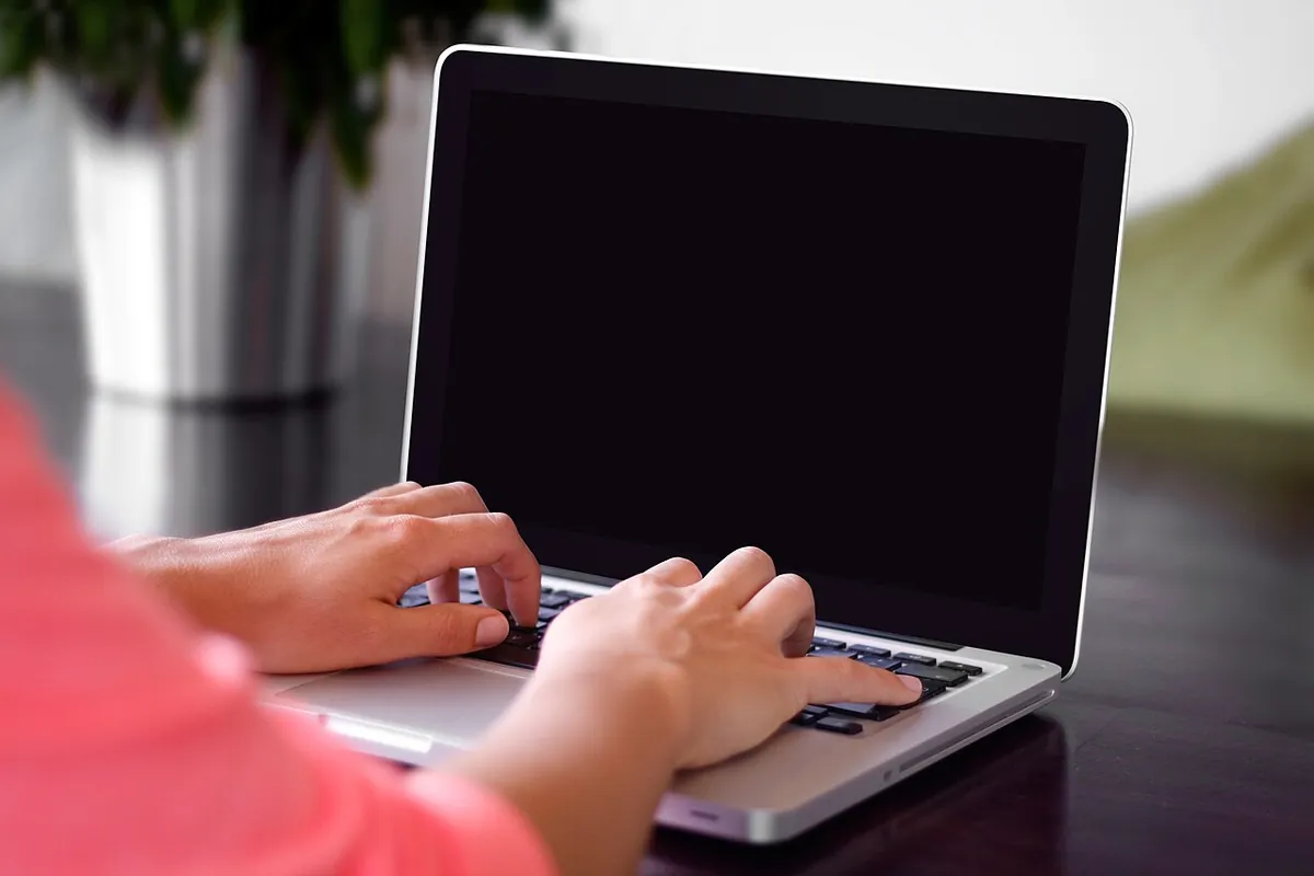 Des mains saisissent un formulaire sur un ordinateur portable
