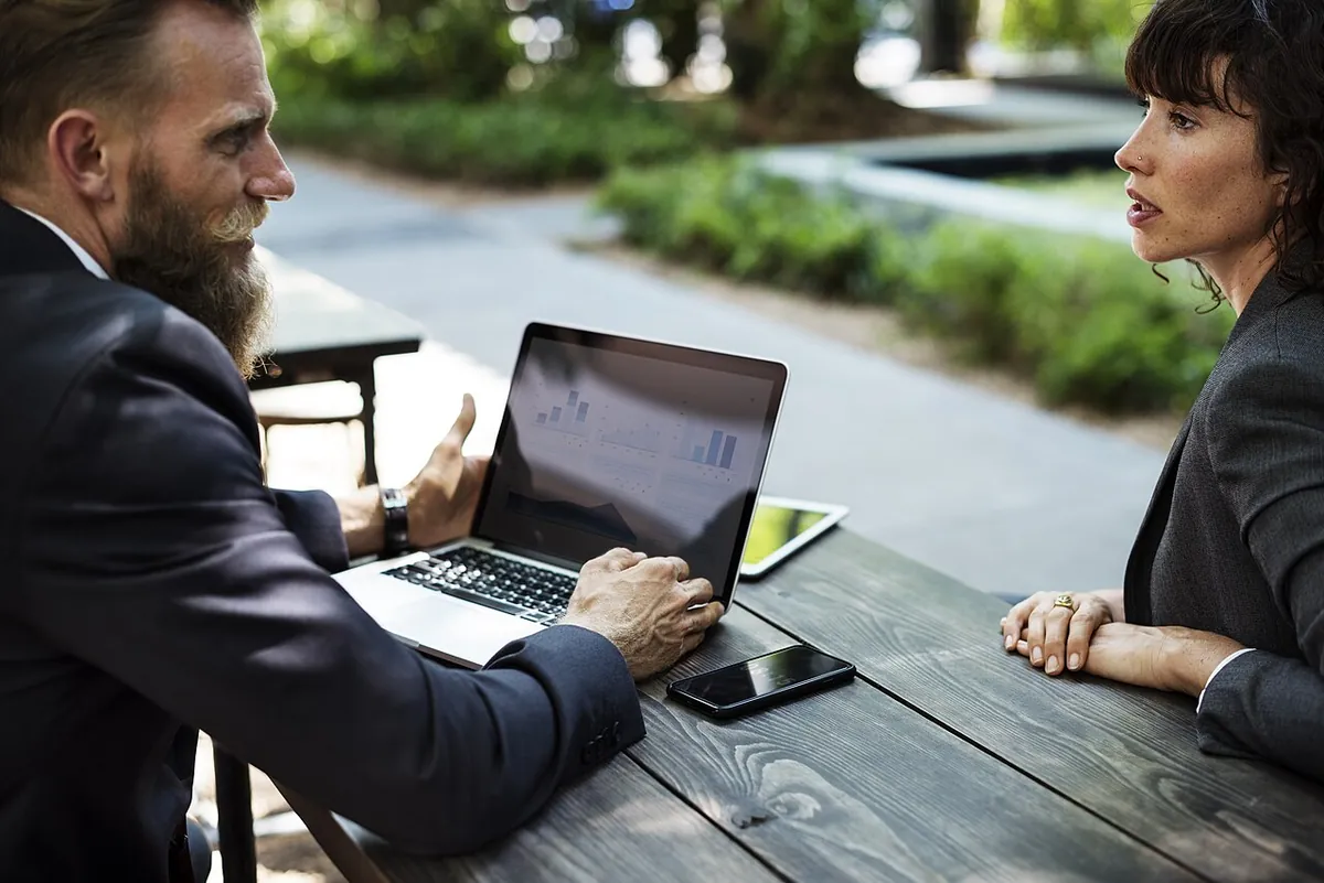 Deux professionnels en rendez-vous autour d’une table, ordinateur ouvert