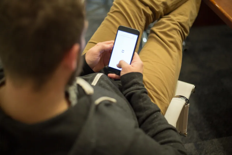 Un homme assis consulte un moteur de recherche sur son téléphone pour comparer des assurances