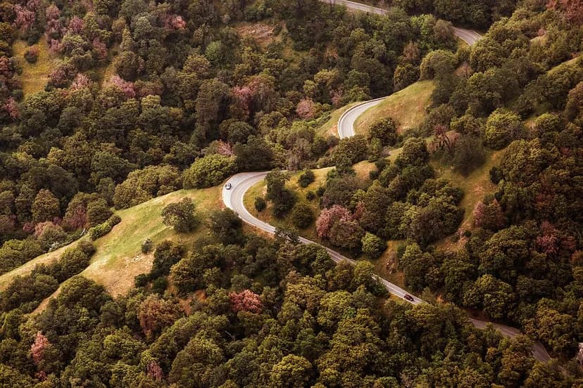 Route sinueuse vue du ciel, serpentant à travers une forêt de collines
